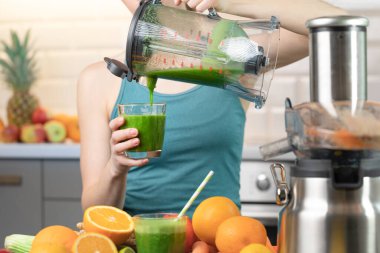 Young women preparing a vegetarian healthy smoothie for detox and preparing for sport exercise.