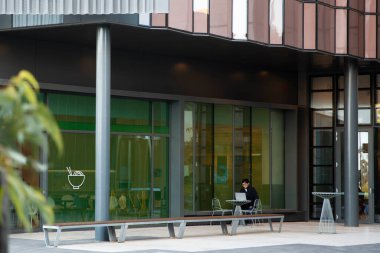 Melbourne, Victoria, Avustralya - 17 Mayıs 2020: Genç adam dizüstü bilgisayarına odaklanmış, özenle bir üniversite kafesinde çalışıyor.