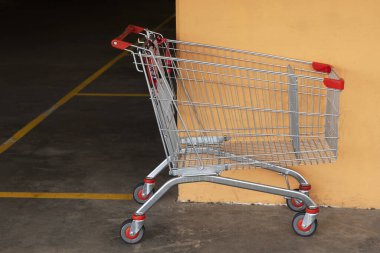 Alışveriş merkezinin otoparkında terk edilmiş bir alışveriş arabası. Bölgede ihmal ve kargaşa olduğunu gösteriyor..