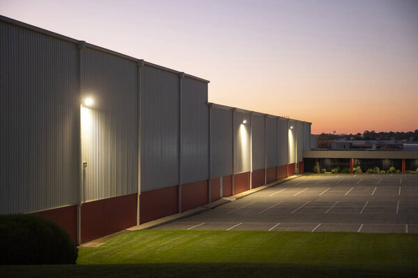 Empty industrial car park in front of a warehouse, capturing the scene during the dusk hours.