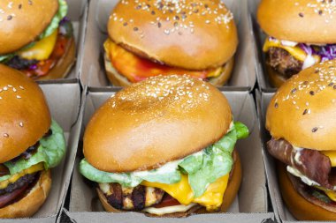 Karton kutuların içine yerleştirilmiş iştah açıcı hamburgerlerin yakın plan perspektifi.