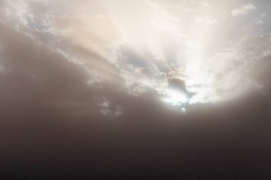 Güneş ışığı gökyüzündeki bulutların arasından doğuyor, resim gibi bir manzara yaratıyor..