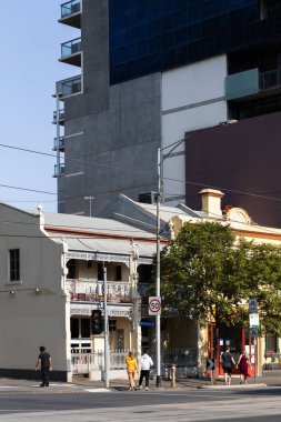 Yoğun bir şehir kavşağında yürüyen genç insanlar, canlı şehir atmosferiyle meşguller..