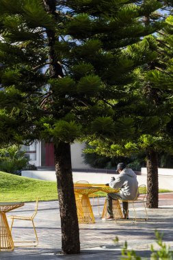 Dışarıdaki oturma yerinde oturan adam, çevrenin ve rahatlığın tadını çıkarıyor..