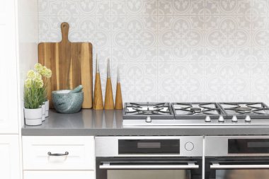 Çift fırın, beyaz tezgah ve işlevsel kesme tahtaları olan modern mutfak..