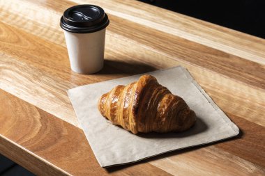 Ayçöreği ve paket kahveyi kağıt bardakta, ahşap bir arka planda..