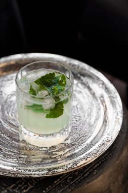 Gümüş tepside taze nane yaprakları ve buz küpleriyle süslenmiş mojito kokteyli..