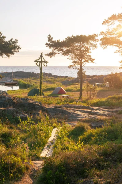 太阳升起了一个经典的中等身材的杆子与小帐篷与露营者在罗斯拉根的海岸线 免版税图库图片