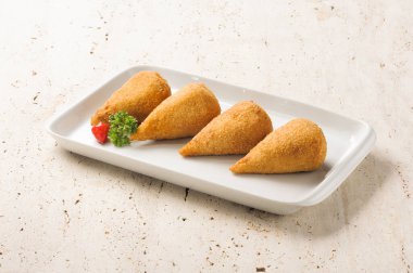 Beyaz bir tabakta dört coxinha, Brezilya 'da kıyılmış veya doğranmış hamur kaplı, gözyaşı damlasına benzeyen bir şekle bürünmüş, parçalanmış veya parçalanmış tavuk etinden oluşan popüler bir yemek..