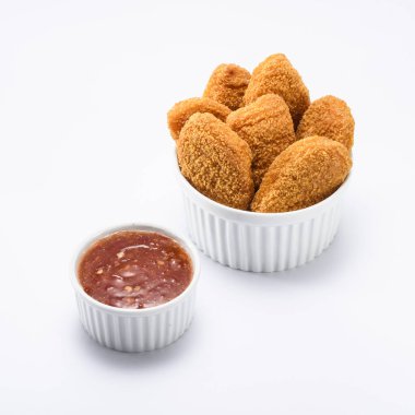 Lezzetli tavuk nuggetları, beyaz bir ramekin üzerinde, yanında ketçap, izole edilmiş. 