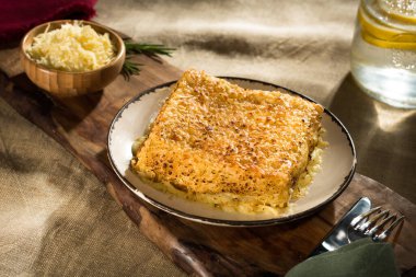 Ahşap bir tahtada, rendelenmiş peynirle birlikte.