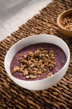 Tahta bir çubuk altlığı üzerinde tahıl gevreği olan bir kase aai.