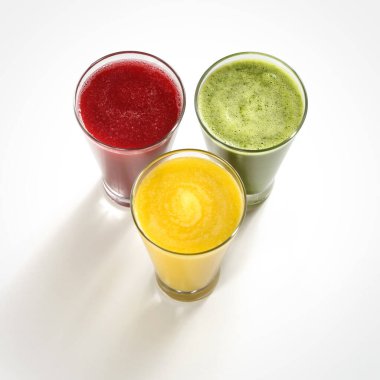 Üç renkli meyve suyu, mango, üzüm, kavun, lahana, pancar, kireç, gölgeli beyaz bir arka plan.
