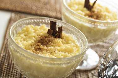 Rice pudding, a delicious dessert made from rice mixed with water or milk and other ingredients such as cinnamon. Served on a glass dessert bowl. clipart