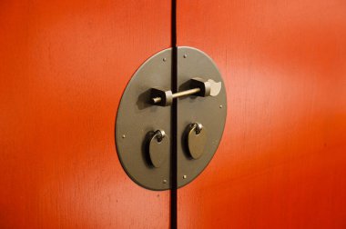 Kapı Asya tarzı, altın çelikten yapılmış, turuncu ahşap bir kapı üzerinde.