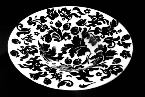 White plate with black ornaments, on black background