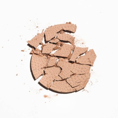 Beyaz arka planda parçalanmış bir makyaj ürünü.