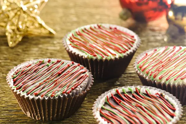Noel kekleri, kırmızı ve yeşil çiselemeli, noel yıldızlı ve toplu, ahşap bir masada.