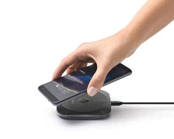 Beyaz el, kablosuz şarj cihazına akıllı telefon koyuyor, beyaz üzerine izole edilmiş.