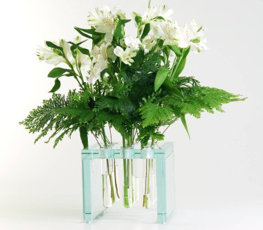 Test tüpleri ve zambaklarla izole edilmiş modern cam vazo.