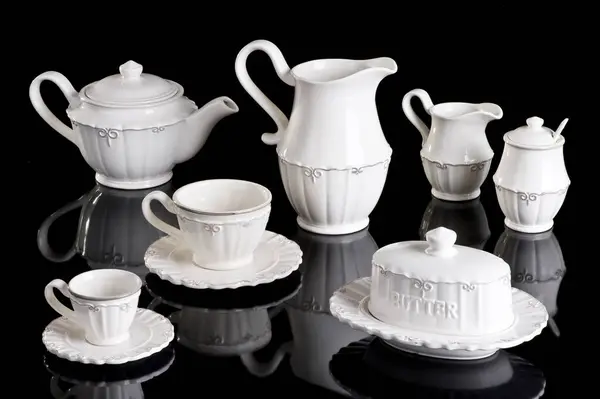 Afternoon white ceramic tea kit with cups, jars, butter dispenser, kettle and sugar bowl, isolated on white