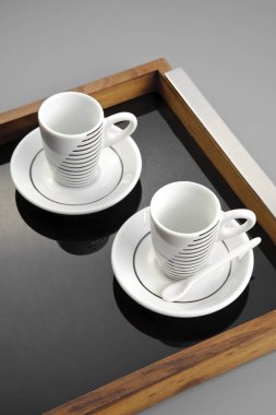 Çizgili iki boş seramik bardak, cam tepside.