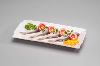 Dikdörtgen seramik servis tabağı, balık, domates, yeşil ve sarı dolma biber, beyaz üzerine izole edilmiş.