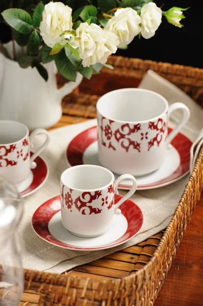 Hasır tepside kırmızı arabesk desenli seramik kaplar.