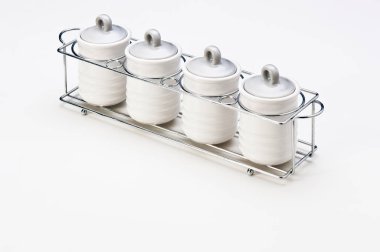 Metal destekli dört küçük beyaz seramik kap seti, beyaz üzerine izole edilmiş.