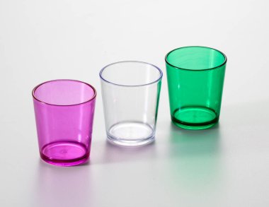 Farklı renklerde üç bardak, mor, beyaz ve yeşil. Beyaz bir arkaplanda izole edilmiş.