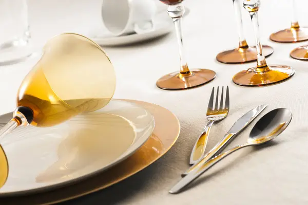 Tabakların üstündeki kehribar şarap bardağını kapayın. Süslü bir masa üstünde. Pastel tonuyla ve sabah ışığıyla.