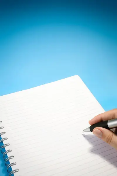 Elinizde tükenmez kalem var, bir kağıda not defterinden alıntılar yazmak üzeresiniz. Arkaplan mavi ve eğimli..