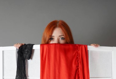 Gülümseyen genç bir kadın Japon paravanı üzerinden bakıyor soyunurken ya da üstünü değiştirirken.