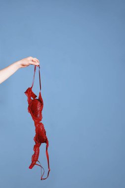 Kırmızı sütyen gösteren kadın eli mavi arka planda fotokopi alanı ile