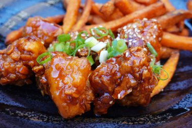 Susamlı kızarmış Kore tavuğu, yeşil soğan ve patates kızartması.