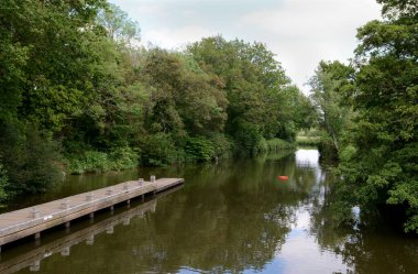 Medway river at Golden Green in Kent, England; a red lifebelt floats on the water at the end of a jetty clipart