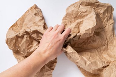 Brown crumpled paper ball, in woman hand isolated
