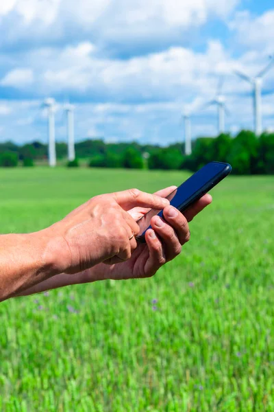 Wind Energy Power Station and hand holding smart phone