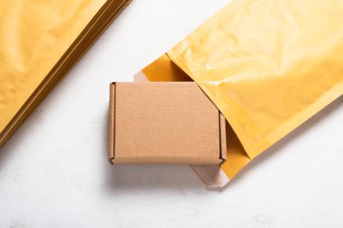 Karton kutu ve baloncuklu posta kutusu beyaz tahta masanın üstünde.