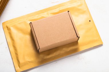 Karton kutu ve baloncuklu posta kutusu beyaz tahta masanın üstünde.