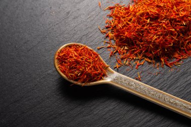 seramik kaşığın içindeki safran baharatı siyah taş arka planda