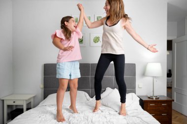 Aile eğlencesi. Anne ve kızı yatakta zıplıyorlar. Yüksek kalite fotoğraf
