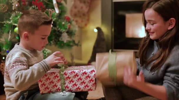 Χαρούμενα Παιδιά Ανοίγουν Χριστουγεννιάτικα Δώρα Στο Σπίτι Κοντά Στο Χριστουγεννιάτικο — Αρχείο Βίντεο