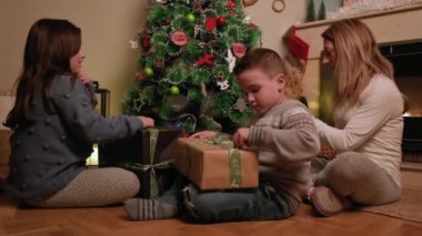Mutlu bir aile ve küçük kızı ve oğlu Noel sabahı birlikte hediyelerin açılışının keyfini çıkarıyorlar. Yüksek kalite 4k görüntü