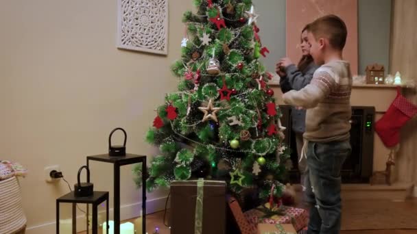 아이들은 아름다운 거실에 전통적 장소로 크리스마스 트리를 장식합니다 고품질 — 비디오