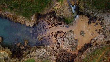 Okyanus dalgalarının yukarıdan görünüşü kayalara çarpıyor. Yüksek kalite 4k görüntü