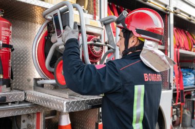 İtfaiyeci kontrol ve bakım ekipmanları itfaiye arabasının yanındaki şömine dairesinde çalışıyor. Yüksek kaliteli fotoğrafçılık.
