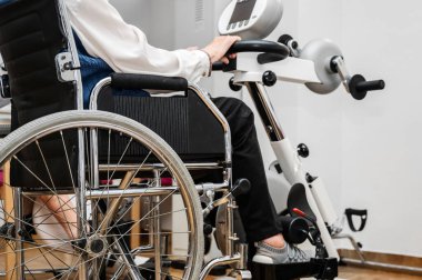 Tanınmayan yaşlı bir kadın hastanede tekerlekli sandalyeden pedal egzersizi yapıyor. Yüksek kalite fotoğraf.