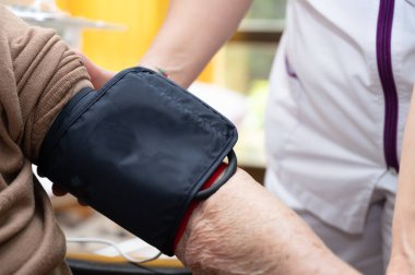 Bakımevindeki yaşlı kadın elinin tansiyonunu ayarlamak için çalışan hemşirenin elini kapat. Yüksek kalite fotoğraf