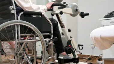 Tanınmayan yaşlı bir kadın hastanede tekerlekli sandalyeden pedal egzersizi yapıyor. Yüksek kalite fotoğraf.